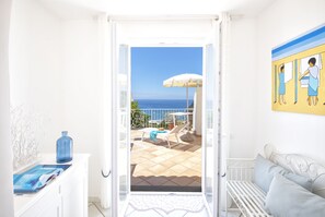 A room with a view of the sea, a white sofa, a blue vase, and a painting on the wall. - Villa dei Lecci Blu - Luxury Villa with a Terrace by the Sea (Forio)