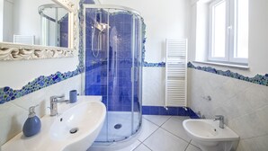 A bathroom with a glass-enclosed shower, two sinks, a mirror with ornate detailing, and a window. - Villa dei Lecci Blu - luxury villa with terrace on the sea (Forio)