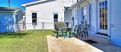 A residential building with a front porch, a small lawn, and a metal fence.