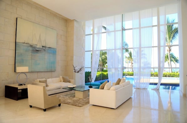 A spacious living room with a large window, a painting, and a pool view.