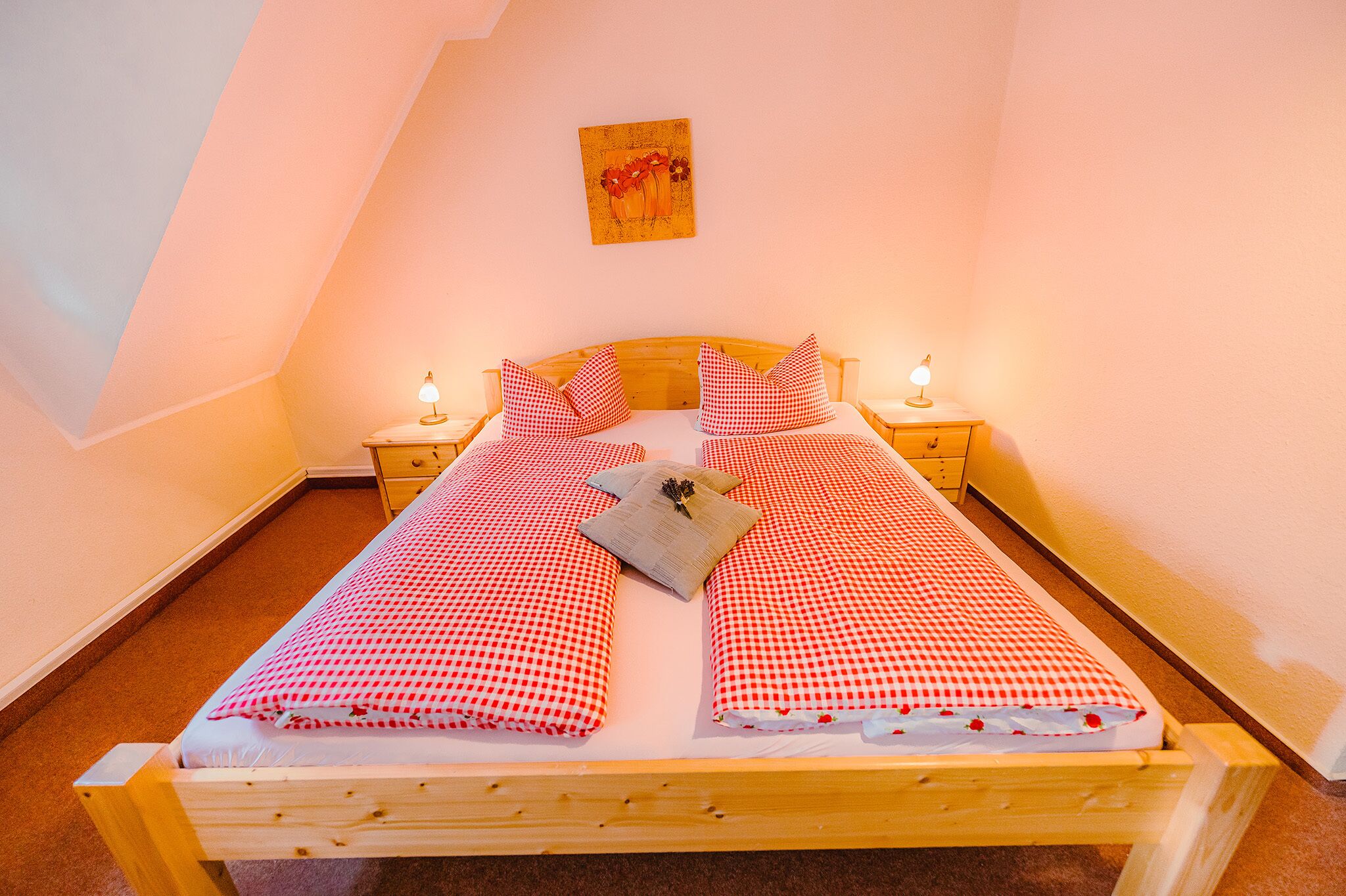 Una cama individual con una colcha a cuadros, dos almohadas, una mesita de noche con una lámpara y un cuadro en la pared.