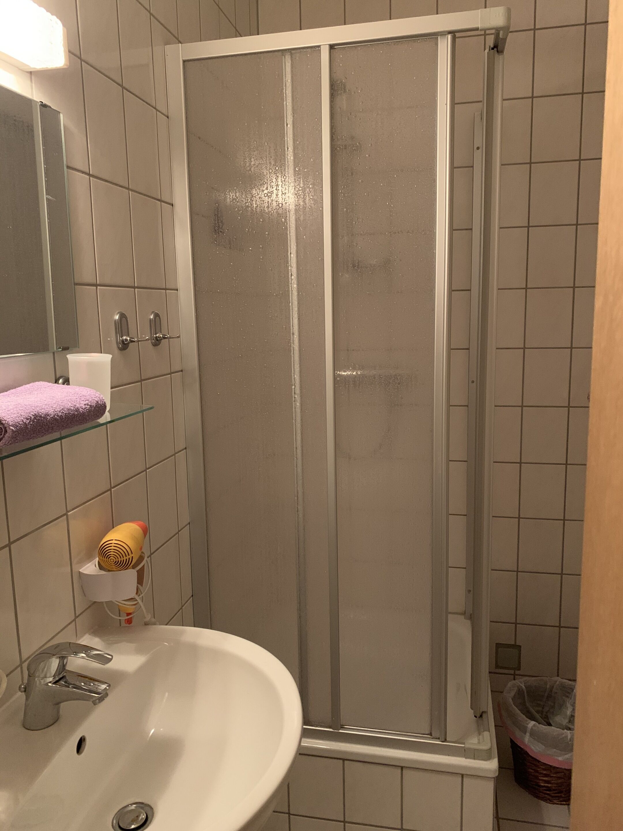 A bathroom with a shower, sink, and mirror.
