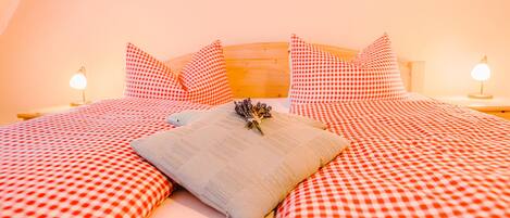 Un dormitorio con colcha a cuadros, dos almohadas y una almohada decorativa, además de lámparas de noche.