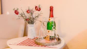A table with a bottle of champagne, a glass, and a vase with flowers.