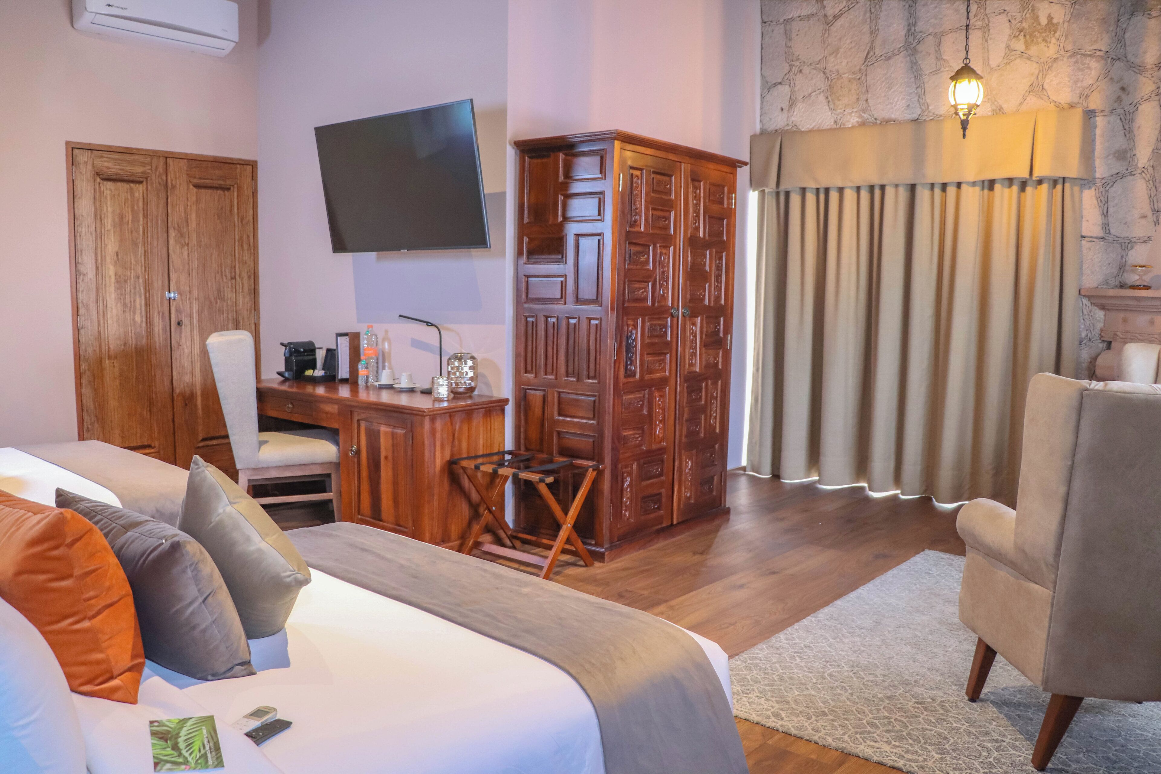 A hotel room with a bed, a desk, a television, a wardrobe, and a chair.