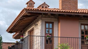 A building with a tiled roof, stone facade, and a balcony with metal railings and flower pots. - Gamma Morelia Vista Bella (Morelia)