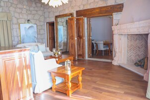 A spacious living room with a stone wall, wooden furniture, and a fireplace.