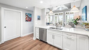 A modern kitchen with white cabinetry, a stainless steel dishwasher, and pendant lighting.