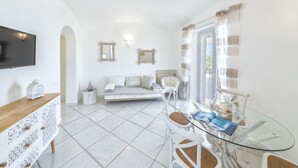 A modern, well-lit room with a glass dining table, white furniture, a sofa, and a TV mounted on the wall. - Villa dei lecci Indaco - Luxury villa on the sea with private jacuzzi (Forio)