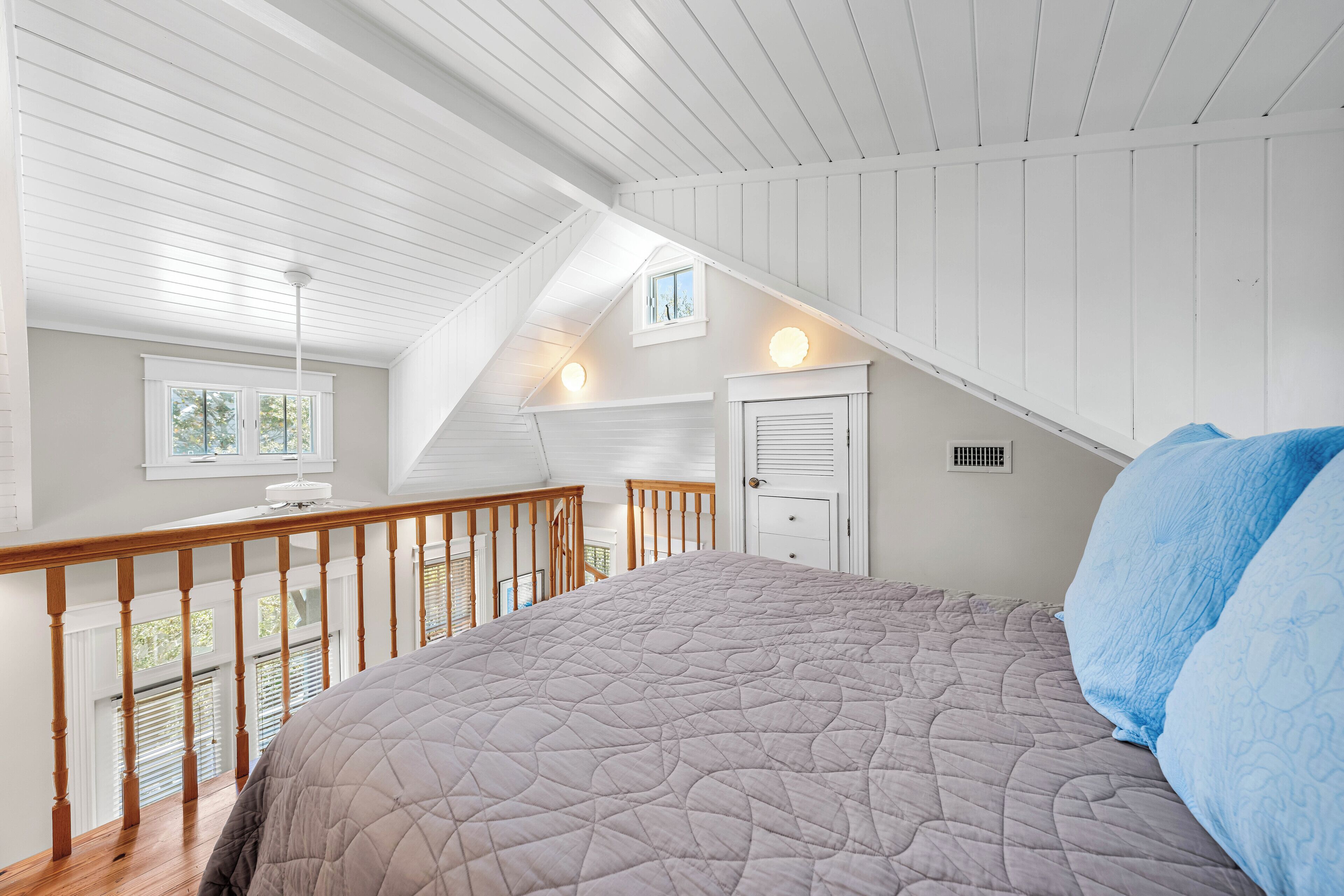 Un dormitorio con una cama grande, barandilla de madera, una ventana y una puerta.