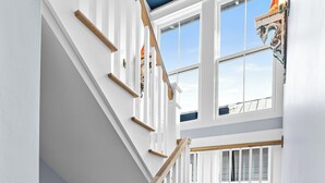Un escalier avec des rampes blanches et des marches en bois menant à un balcon offrant une vue.