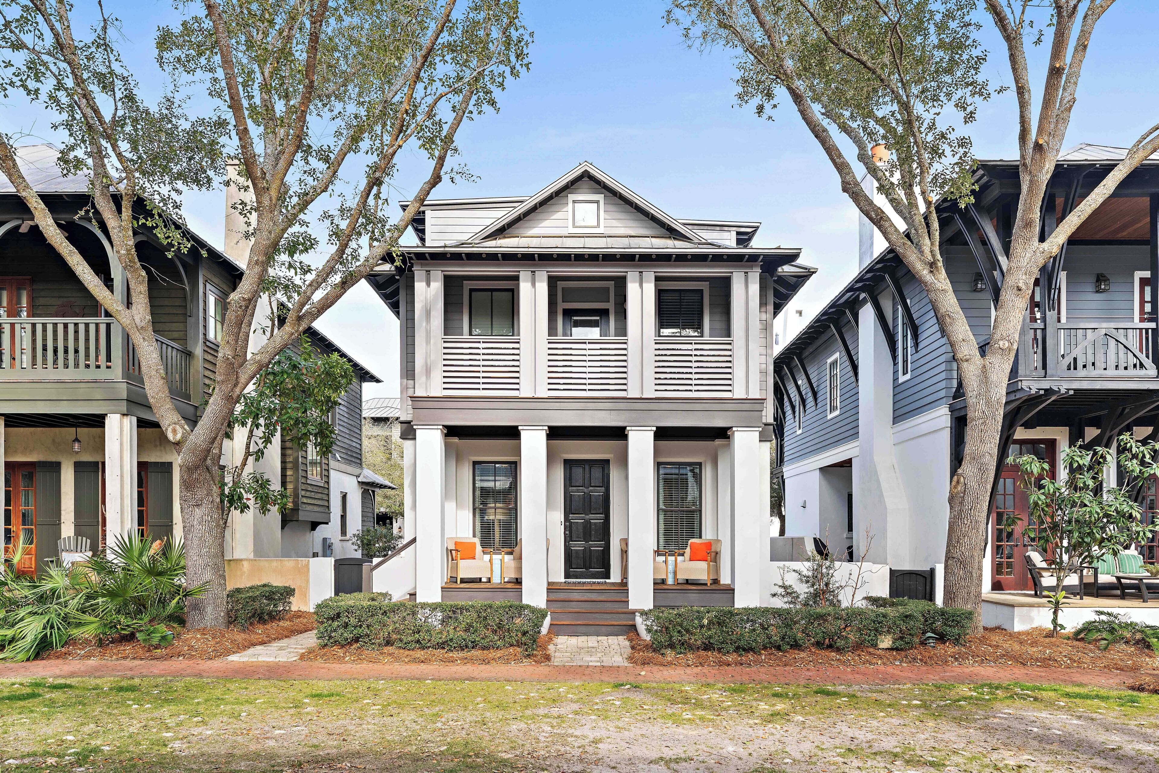 A two-story house with a front porch, columns, and a small garden.