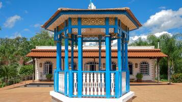 A pavilion with a blue and white color scheme, surrounded by a building with a tiled roof and arched windows.
