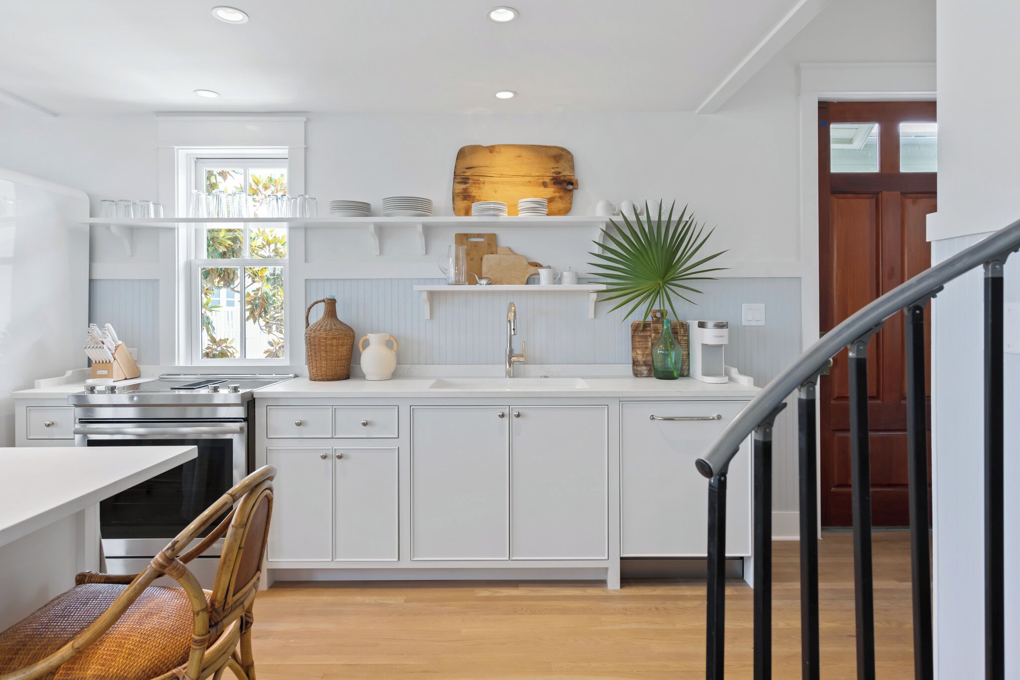 A modern kitchen with white cabinetry, a built-in oven, and a dining area with a table and chairs.