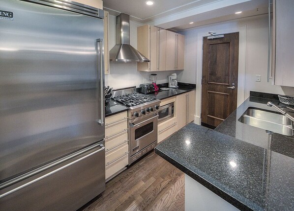 Una cocina moderna con electrodomésticos de acero inoxidable, armarios de madera y encimera de granito.