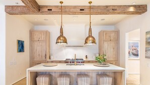 A kitchen with a large island, wooden cabinets, and pendant lights.