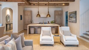 A modern kitchen with wooden beams, pendant lighting, and a central island.