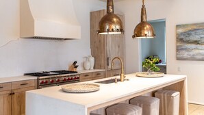 A modern kitchen with a central island, stainless steel appliances, and pendant lighting.