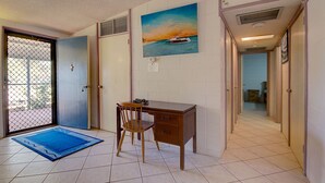 A room with a desk, chair, and a painting of a boat on water.