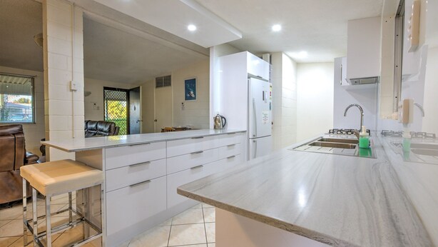 A modern kitchen with white cabinets, a stainless steel refrigerator, a sink, and a countertop.