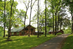 A rustic cabin with a metal roof, surrounded by tall trees and a well-maintained lawn. - Premier property(s) sleeps 36..close to Great Meadow Gold Cup Access (Warrenton)