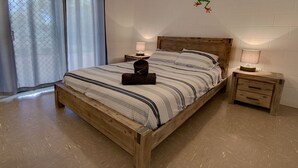 A wooden bed with striped bedding, two bedside tables with lamps, and a window with curtains.