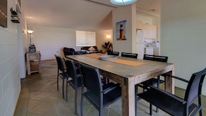 A dining area with a wooden table, six chairs, and a kitchen in the background.