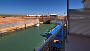 A view of a canal with boats docked on the right, a bridge in the background, and a building with a sloped roof.