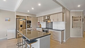 A modern kitchen with a central island, stainless steel appliances, and a tiled backsplash.