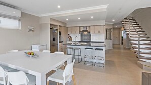 A modern kitchen with a central island, white cabinetry, and a stainless steel refrigerator.