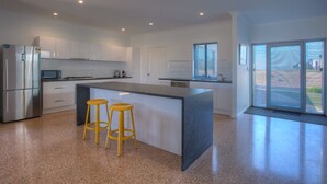 Una cucina moderna con isola centrale, elettrodomestici in acciaio inossidabile e vista all'esterno.