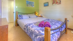 A single bed with a floral bedspread, two pillows, and two rolled towels. - Blue Moon - Family friendly, comfy home. (Exmouth)