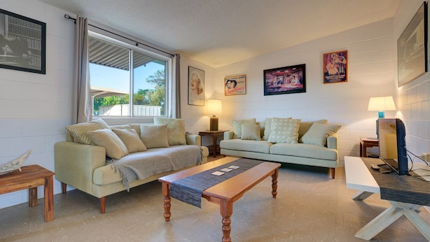 A living room with two sofas, a wooden coffee table, and a TV on a stand. - Blue Moon - Family friendly, comfy home. (Exmouth)