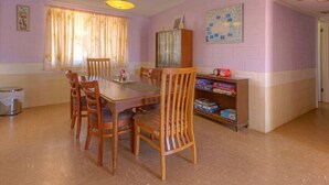 A dining area with a wooden table and chairs, a cabinet with board games, and a map on the wall. - Blue Moon - Family friendly, comfy home. (Exmouth)