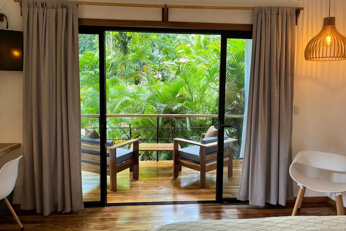 A room with a sliding glass door leading to a balcony with a wooden table and two chairs.