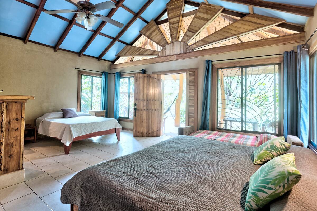 A bedroom with a large bed, a smaller bed, a wooden nightstand, and a ceiling fan.