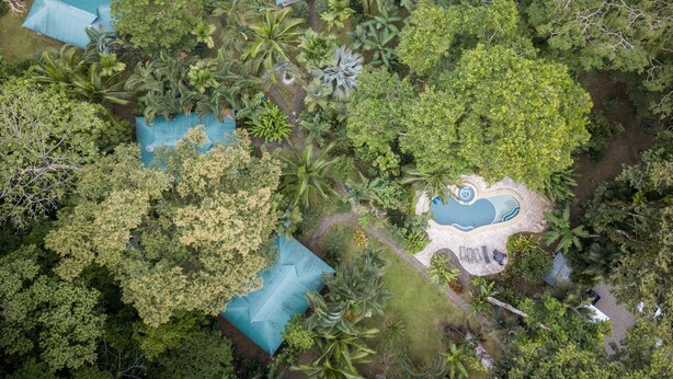 An aerial view of a resort with multiple buildings, a swimming pool, and lush vegetation. - El Nido Jungle Lodge (Cahuita)