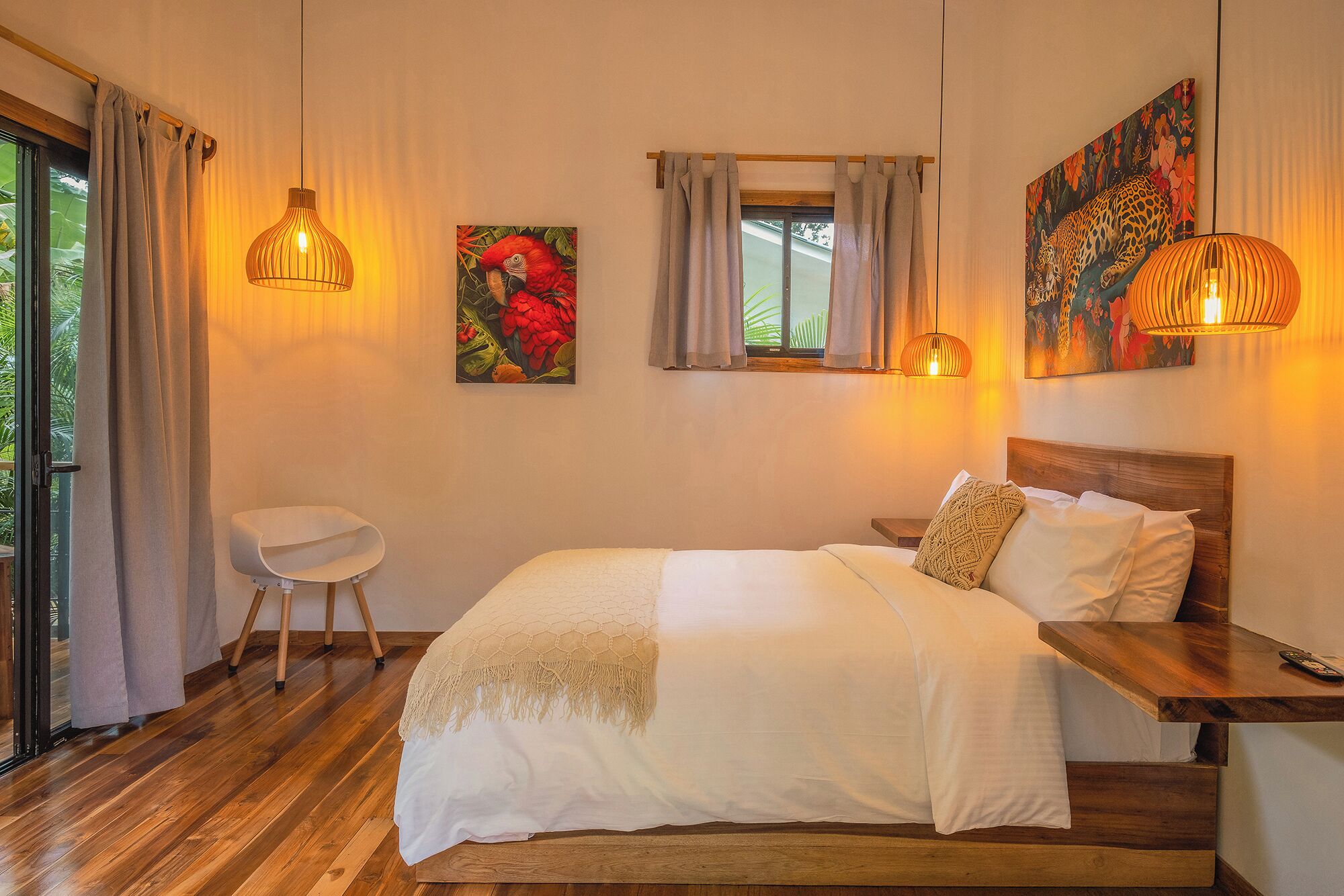 Un dormitorio con una cama de madera, una mesita de noche, una silla y obras de arte en las paredes.