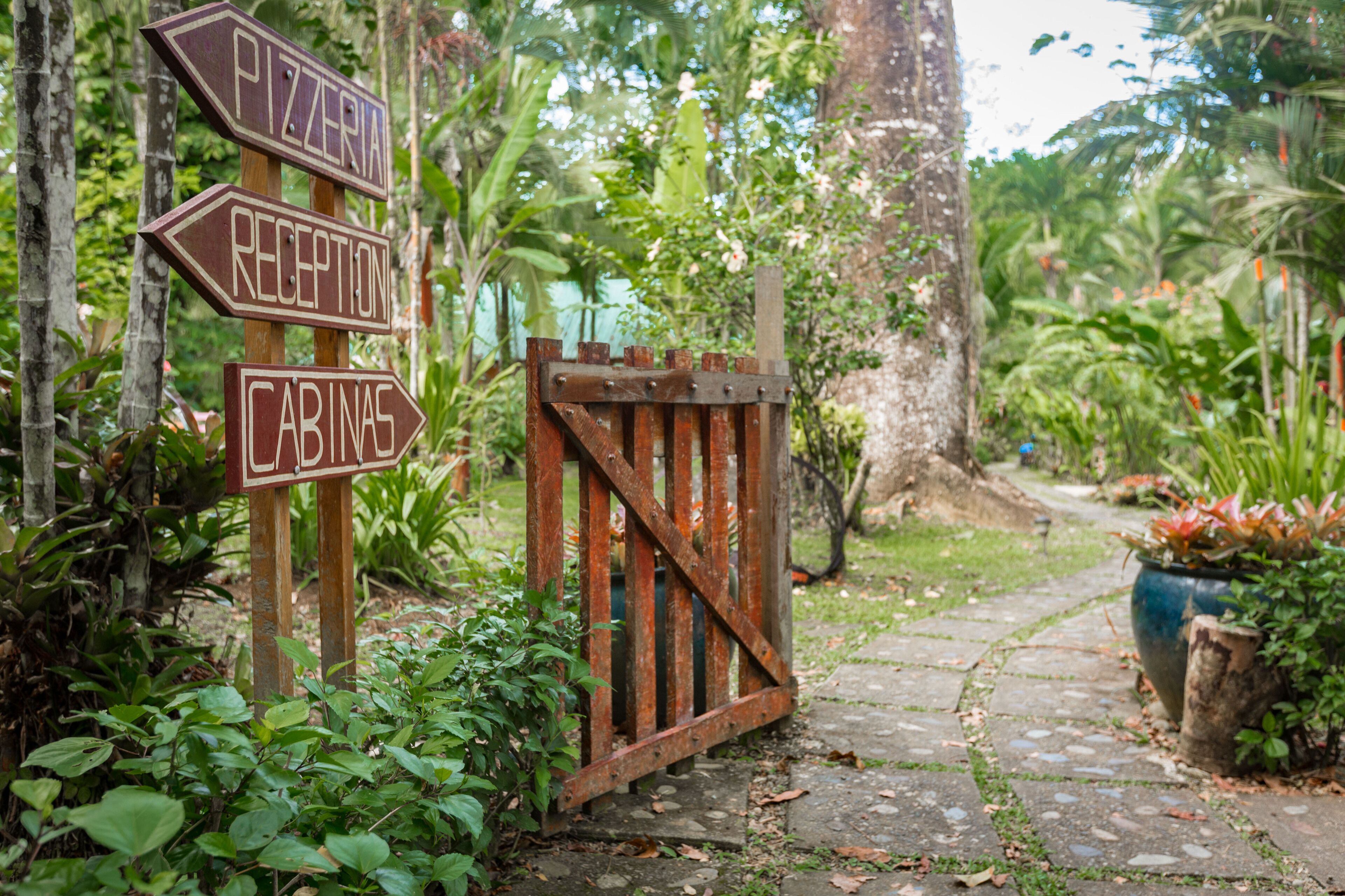 A wooden signpost with directions to 'Pizzeria,' 'Reception,' and 'Cabinas.'