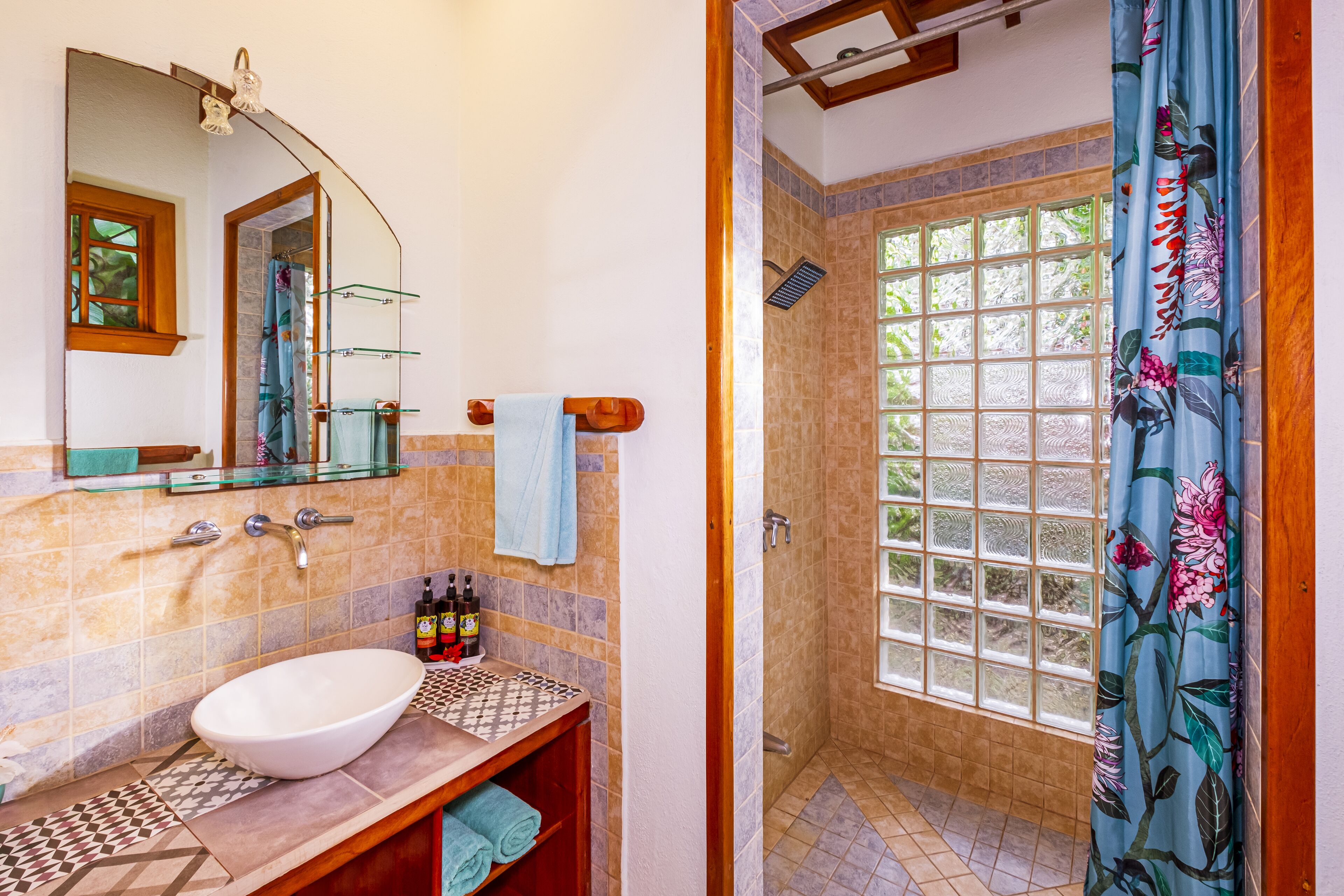 A bathroom with a large window, a sink, and a shower area.