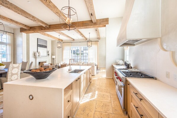 A spacious kitchen with a large island, wooden beams, and a modern stove.