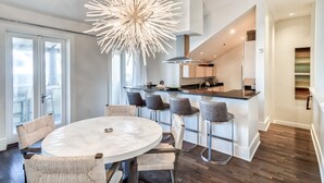 Une cuisine moderne dotée d’un îlot central, de tabourets de bar et d’un coin repas avec une table ronde et des chaises.