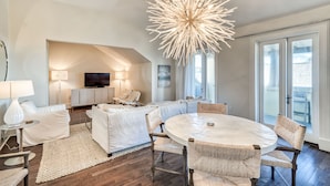Un salon moderne avec une table à manger ronde, des canapés blancs et un lustre original.