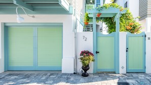 A building with a light blue facade, a number '72' above the entrance, and a potted plant with flowers in front. - Mini Beach Bungalow CH - GULF VIEWS, SOUTH OF 30A. FREE BIKES/GYM/FITNESS (Rosemary Beach)