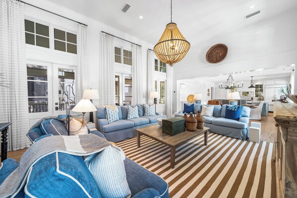 A spacious living room with a large sofa set, a coffee table, and a hanging light fixture.