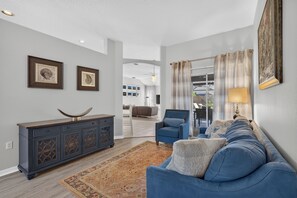 A living room with a blue sofa, a dark wooden cabinet, and a patterned rug.