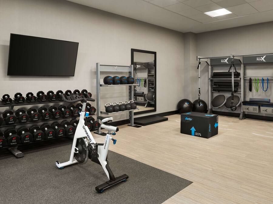 A gym with exercise equipment, including dumbbells, a stationary bike, and a weight rack.