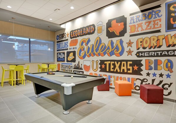 A pool table in a room with a mural featuring various city names and logos. - Tru By Hilton Euless DFW West (Euless)