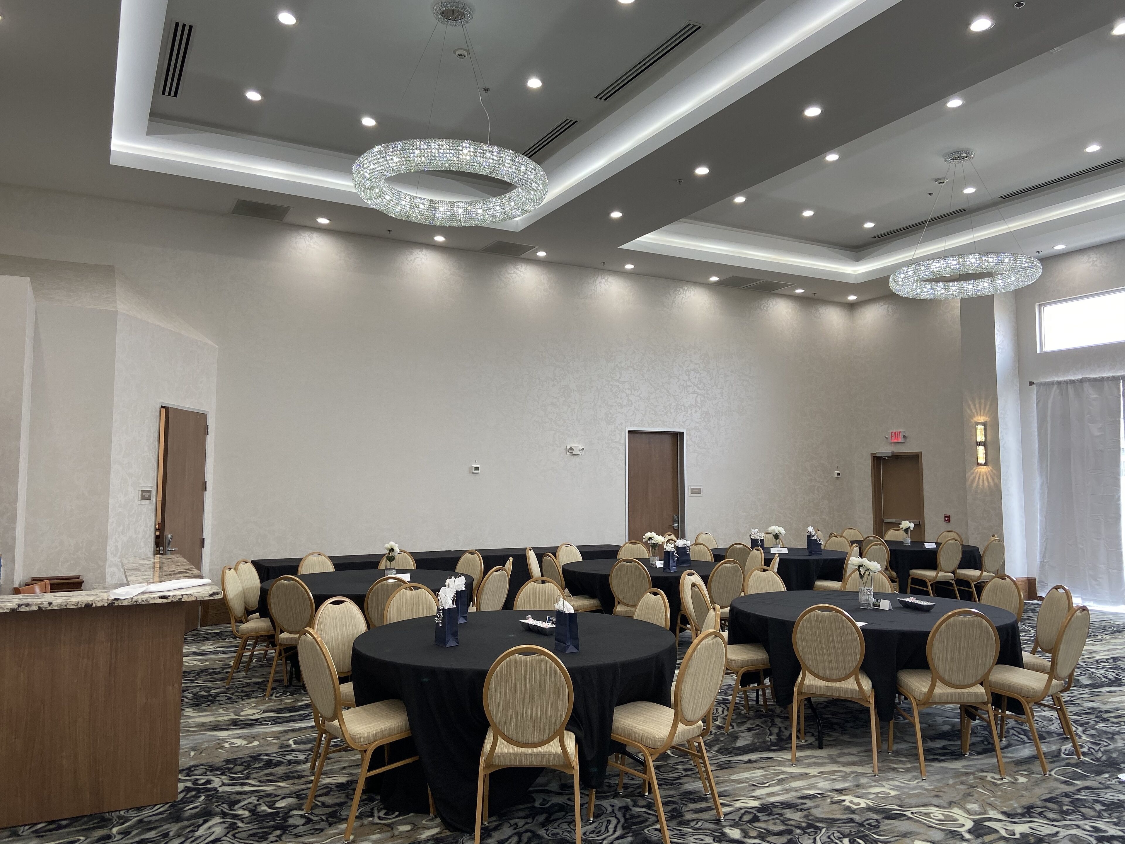 Une salle de conférence équipée de plusieurs tables rondes, de chaises et d’un comptoir d’accueil.