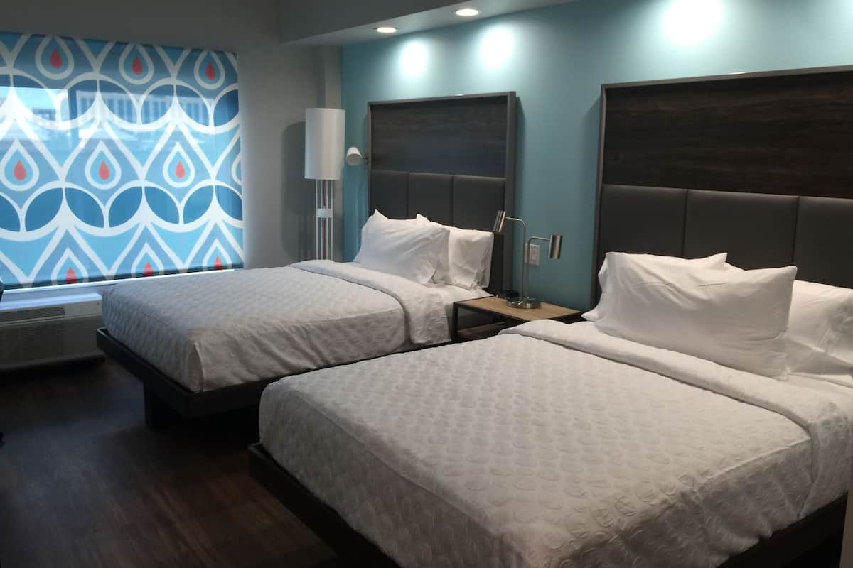 A hotel room with two beds, a patterned wall, and a modern design.
